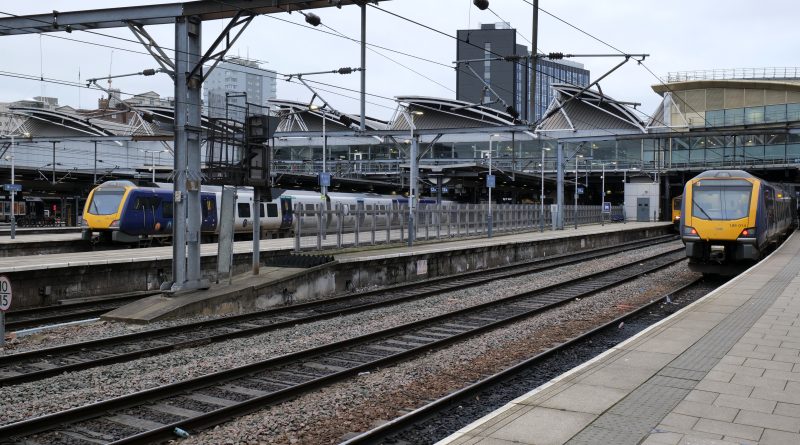 Railway station at Leeds, with two yellow and blue Northern trains waiting at the station.