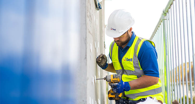 Bell Group worker drilling a hole into a wall