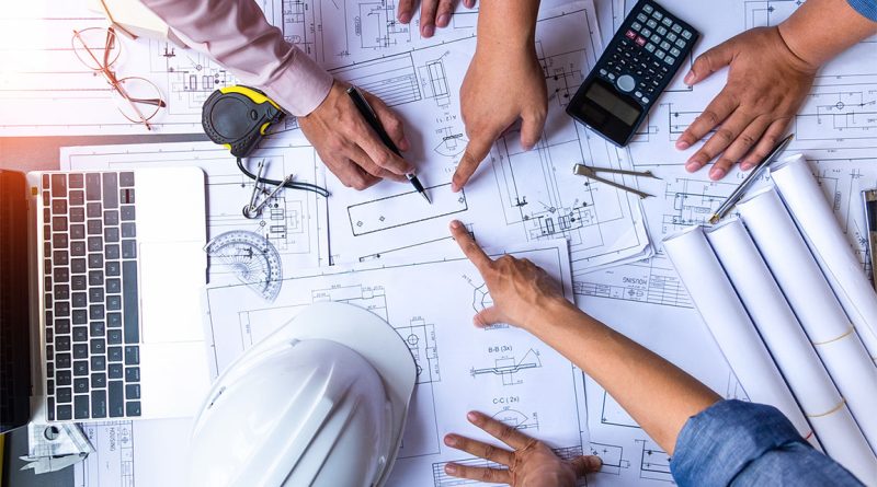 Image of multiple construction workers gathered round a table pointing to various sections of a construction plan to support Birmingham Bridge '13' article