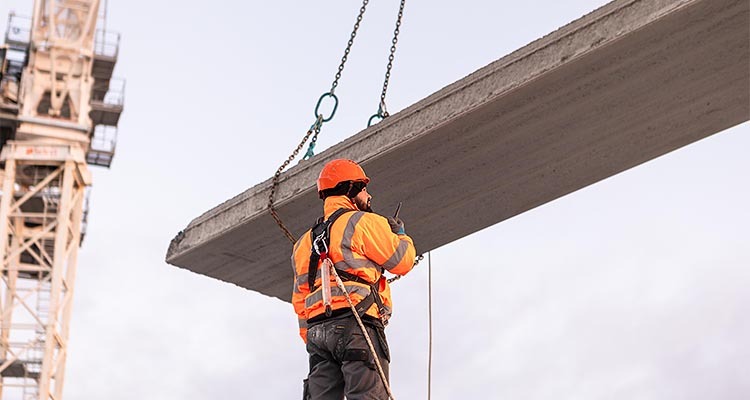 Man standing next to concrete beam on a crane