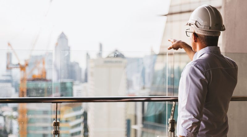 Image of a construction worker stood on a balcony in London pointing at The Shard and skyline to support UK infrastructure article