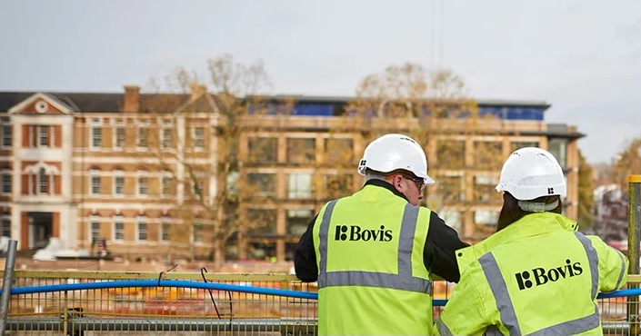 Illustration of construction workers at a UK city project site with Bovis branding reappearing on signage